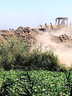 بالفيديو والصور .. معدات حفر ولوادر تلقى مخلفات خرسانية فى مصرف بشمال قنا
